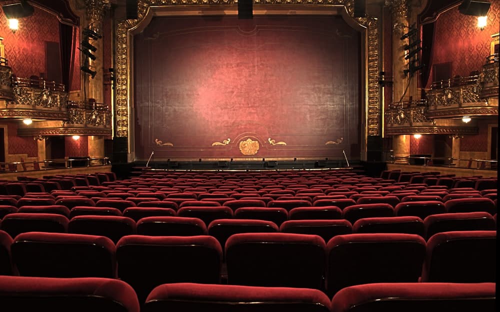 An empty theatre auditorium of numbered red seats facing the stage